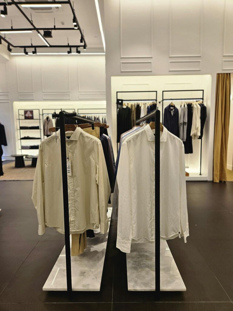 A modern retail store showcasing elegant mens shirts and clothing on display racks.